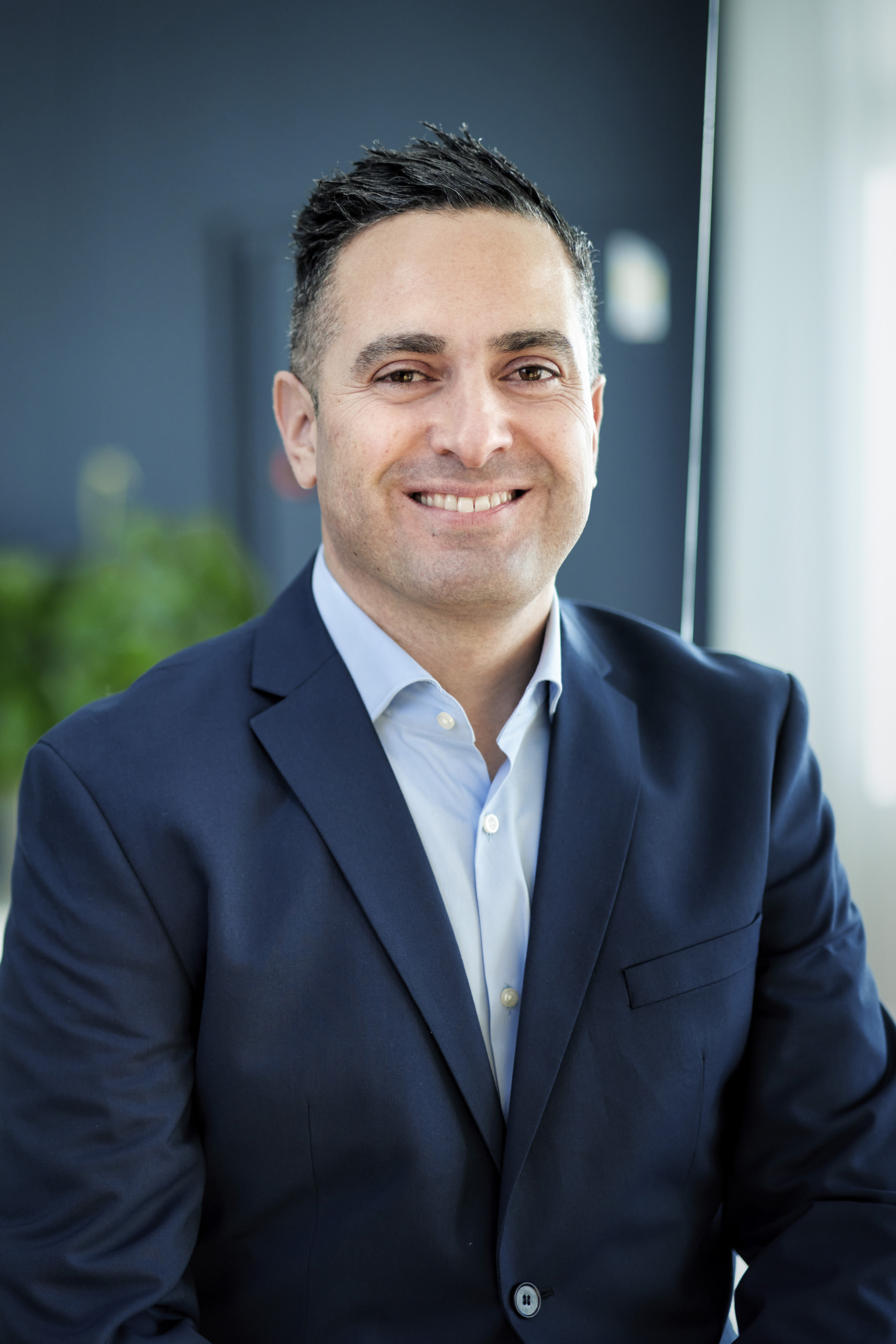 En man i kostym som ler mot kameran.