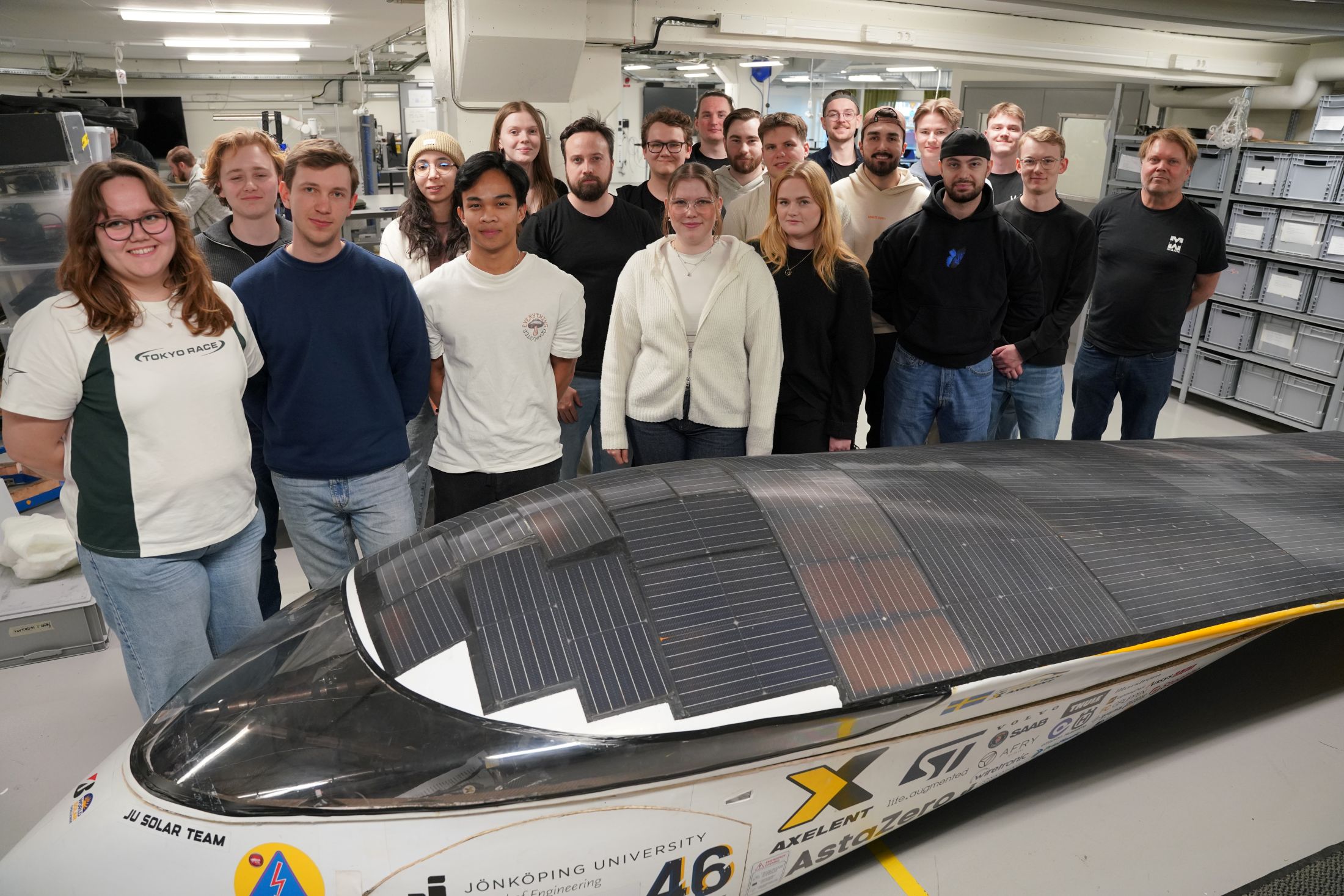 Students and teacher behind a solar car.