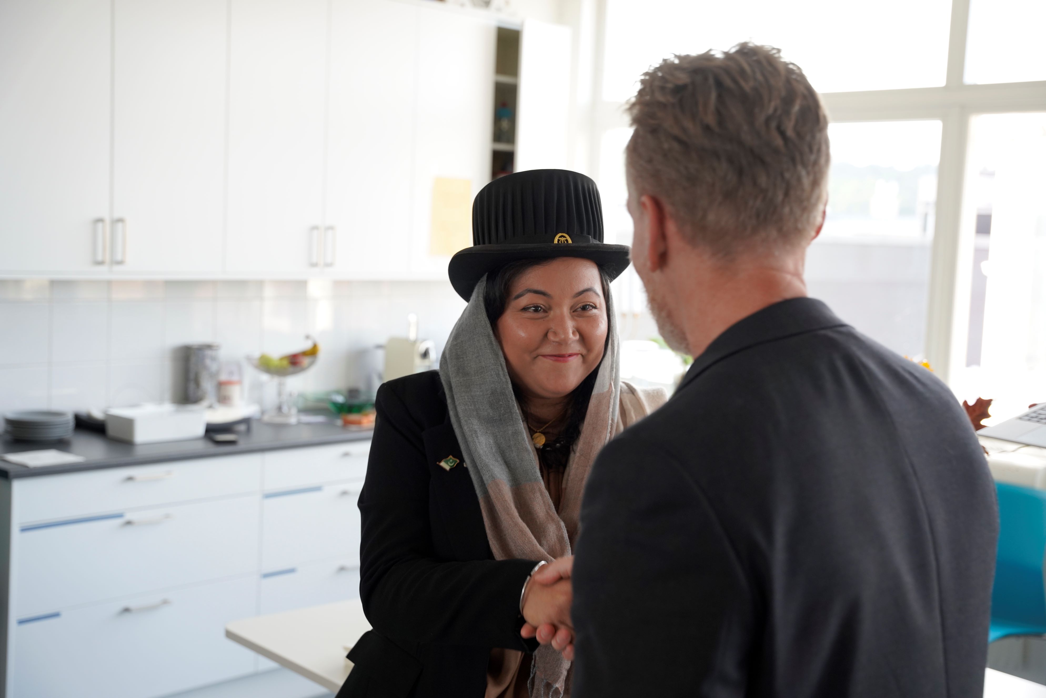 Photo of Rida Ijaz wearing the traditional doctoral hat, smiling and shaking hands after her successful defence.